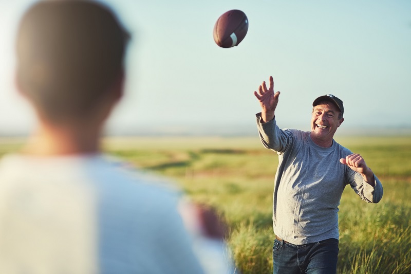 father and son throwing football outside