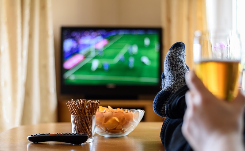 man watching American football with snacks and beer