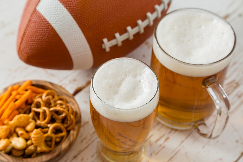 beer next to an American football with snacks