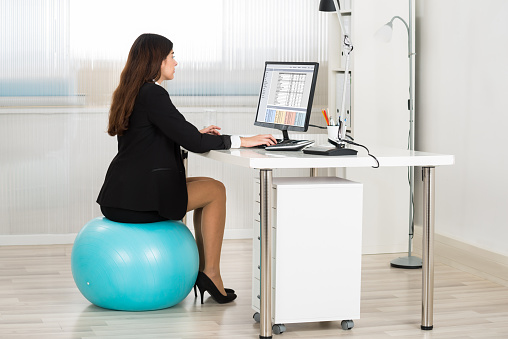 woman sitting on an exercise ball while working