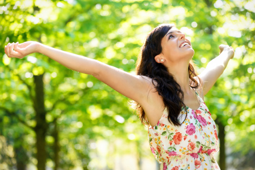 energetic woman outside in nature with arms outstretched