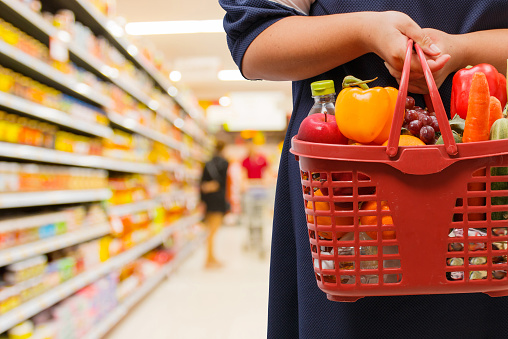 person holding shopping basket filled with groceries