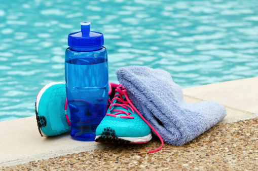 blue water bottle, towel and sneakers next to a swimming pool