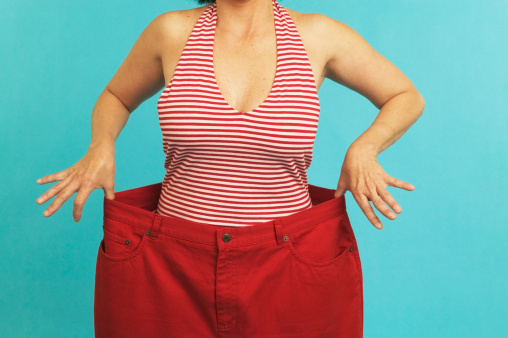 Woman holding up pants that are too large