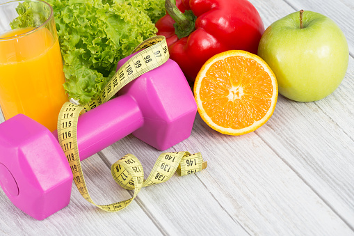 dumbbell and measuring tape with fresh fruits and vegetables