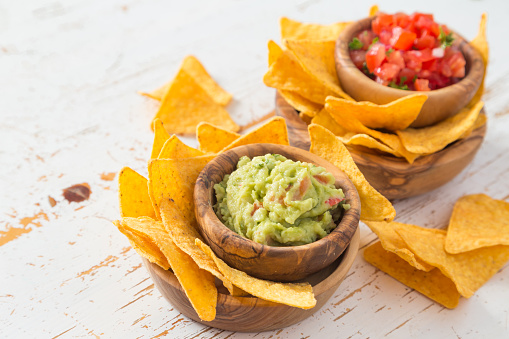 Tortilla Chips in bowls with small bowls of guacamole and salsa
