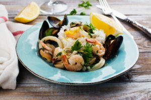 shrimp, mussels and calamari with rice and lemon over a blue plate 