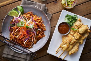 pad thai and chicken satays served on a table