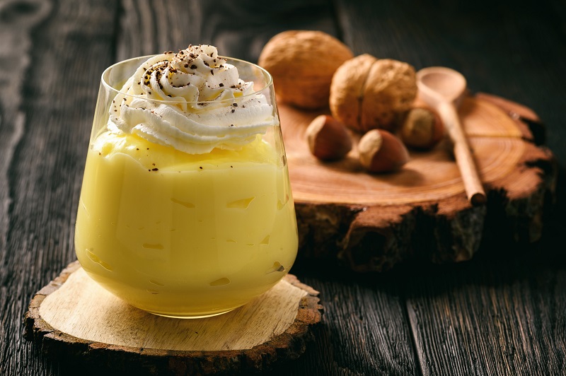 Cream pudding with whipped cream on a wooden background