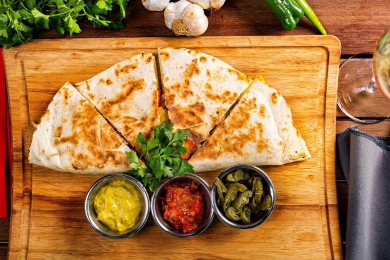 quesadilla on a cutting board with sauces