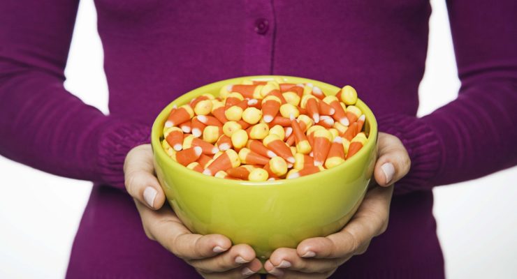 A woman holding a bowl of Halloween candy corn