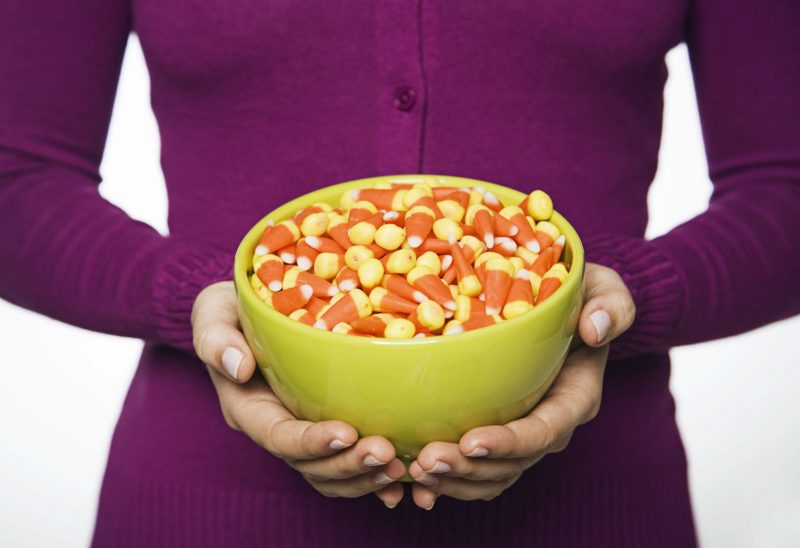 A woman holding a bowl of Halloween candy corn