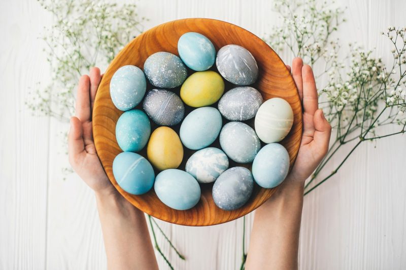 person holding bowl of colorful eggs