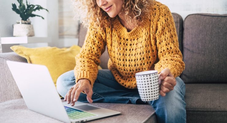 woman on her laptop on the couch drinking coffee