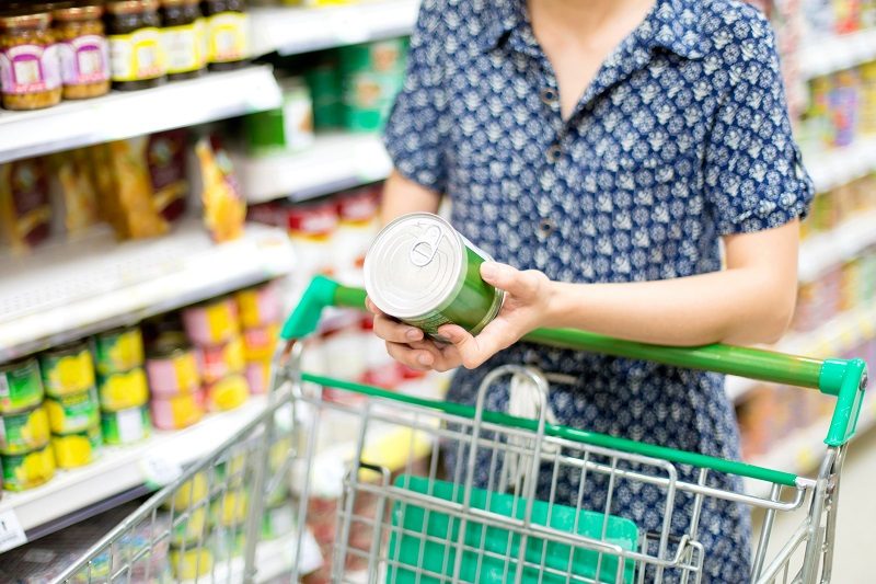 woman looking at a can while shopping at the grocery store
