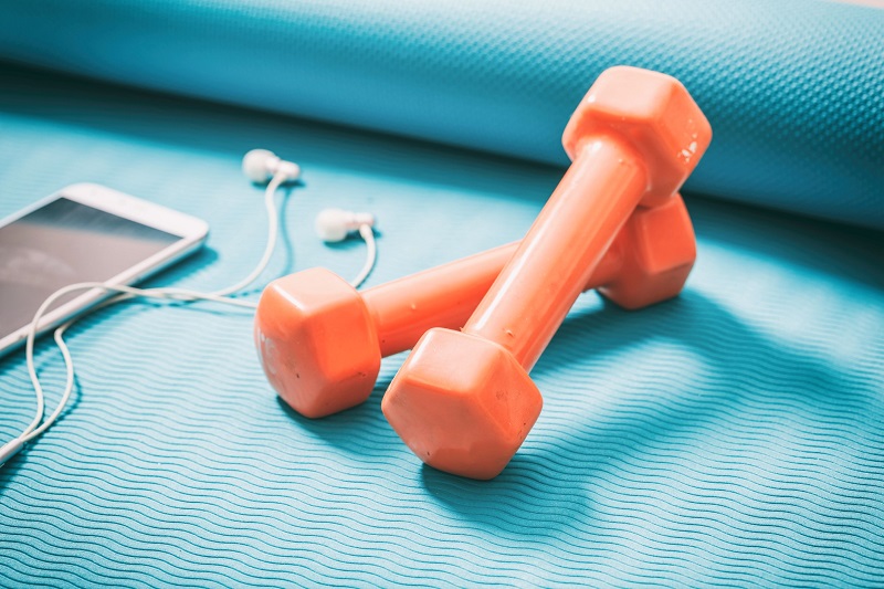 dumbbells and a smart phone on a yoga mat