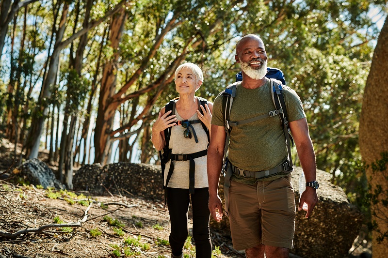 man and woman walking in the woods to burn more calories