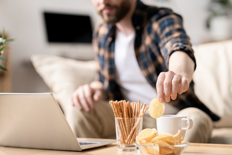 dad snacking while working in the living room. weight loss tips for busy moms and dads