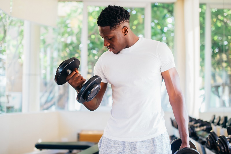 a man exercising by lifting dumbbells. men's metabolism tips