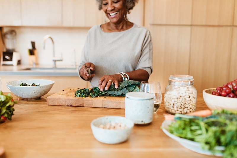 an elderly woman chopping up salad on a cutting board on a personalized weight loss plan