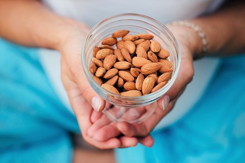 a woman holding a bowl of fresh almonds