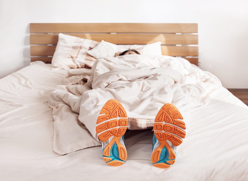 Person napping on bed in workout clothes to get better sleep.