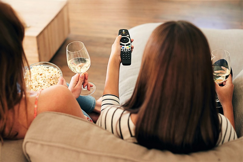 Two women with popcorn and wine in the evening