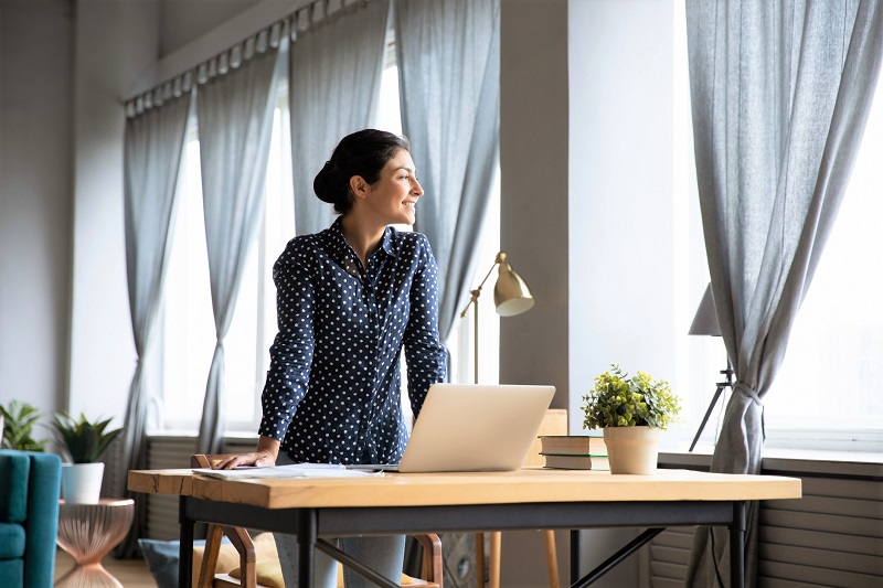 woman standing up at her desk and looking out the window. metabolism boosting tips for women