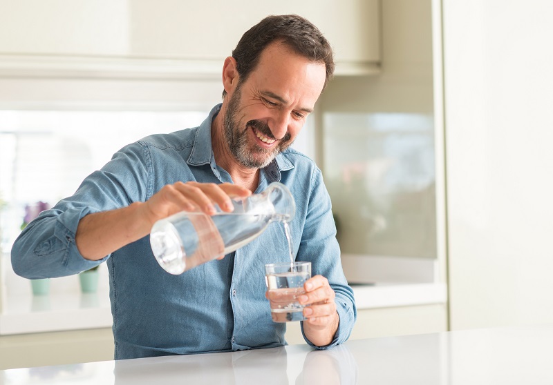 smiling man drinking a fresh glass of water. men's metabolism tips