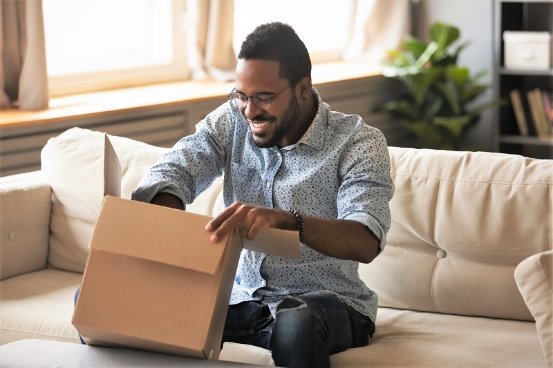 man opening a box on a couch. simple weight loss plan delivered