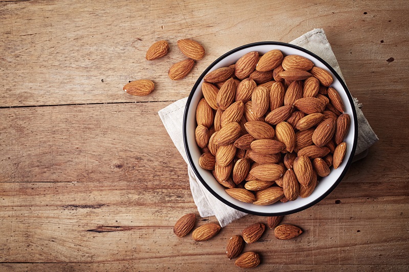Bowl of whole almonds set on a table.