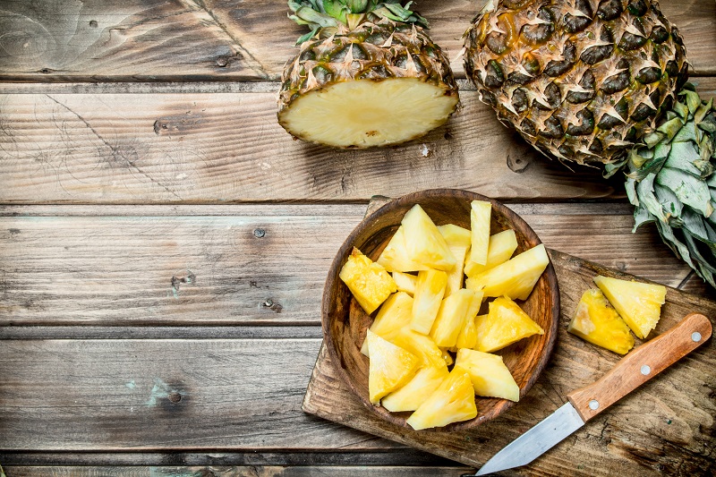 Whole pineapple and pineapple slices on a table. pear shaped body fat loss tips