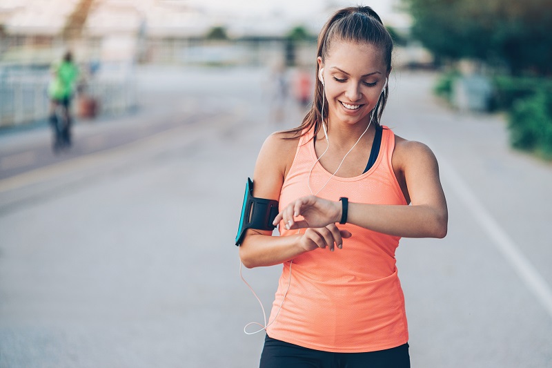 woman in running gear and headphones checking her watch. pear shaped body fat loss