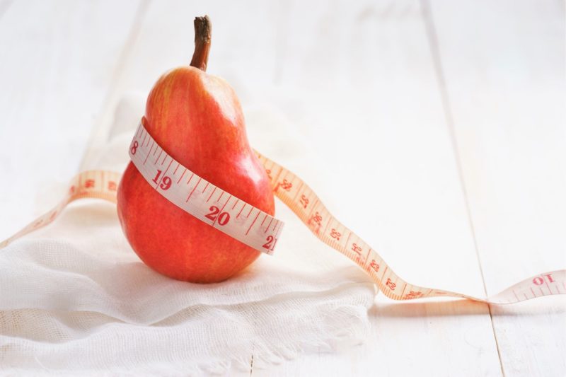 red pear wrapped in a measuring tape