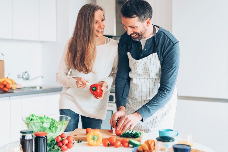 a couple cooking a healthy meal with fresh produce. losing weight after 40