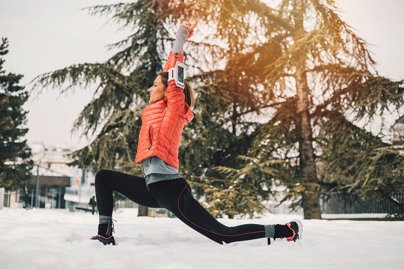 a woman doing outdoor yoga workouts in winter