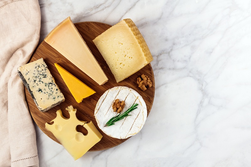 a variety of cheese on a charcuterie board