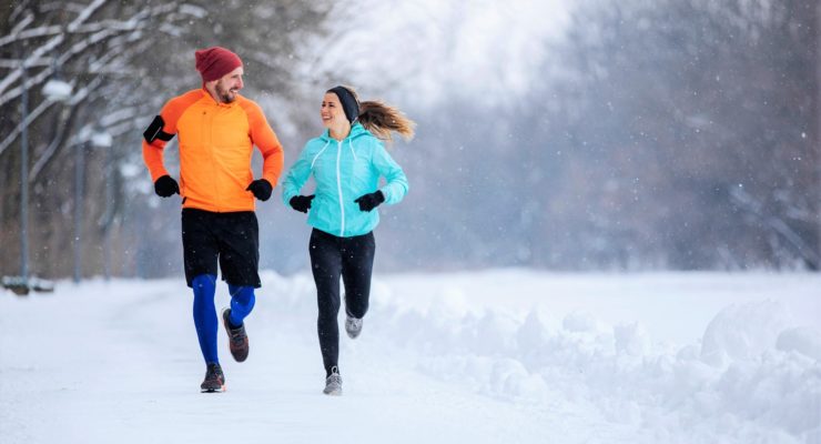 a woman and a man running doing winter workouts, surrounded by snow