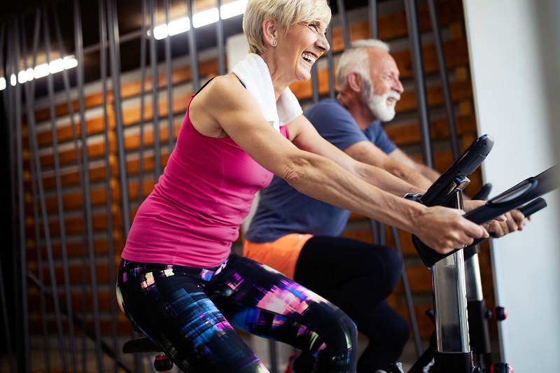 an elderly couple exercising on an indoor cycling bike