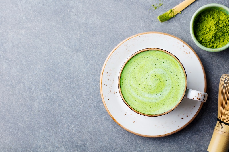 a cup of matcha green tea with a cup of raw matcha powder