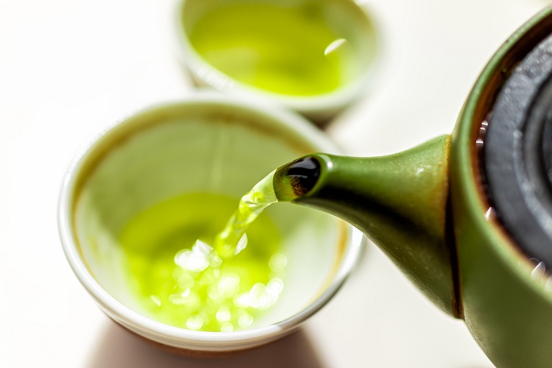green tea being poured into a small tea cup