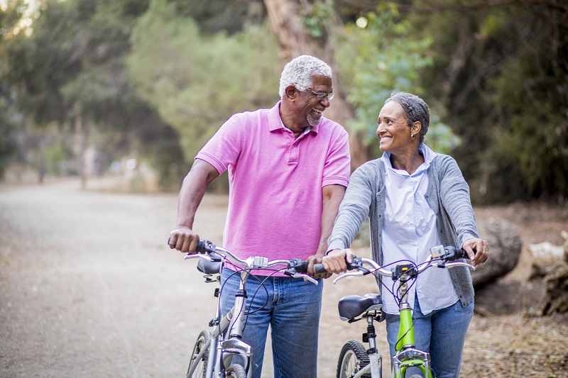 elderly couple enjoying a walk in the park with their bikes