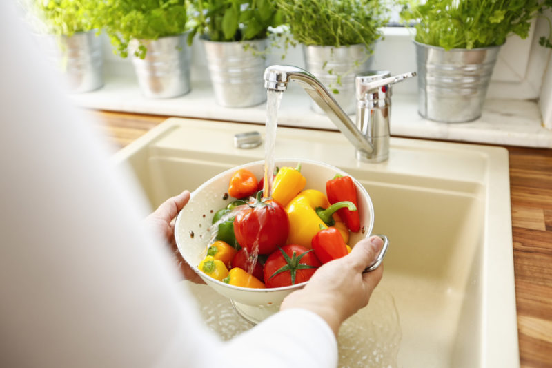 woman washing peppers and tomatoes