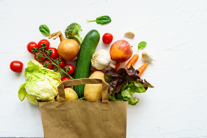 a grocery bag overflowing with vegetables