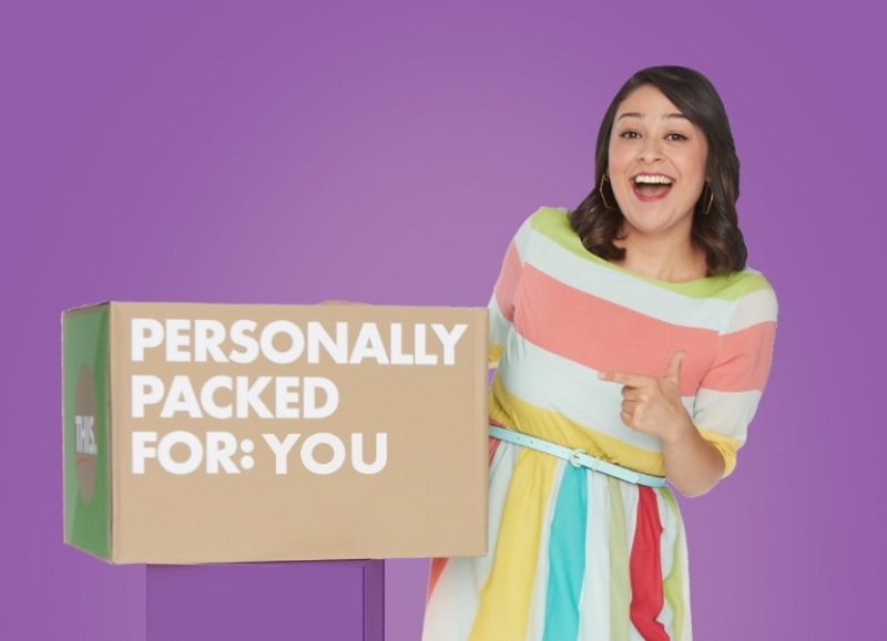 a smiling woman pointing to a meal delivery package