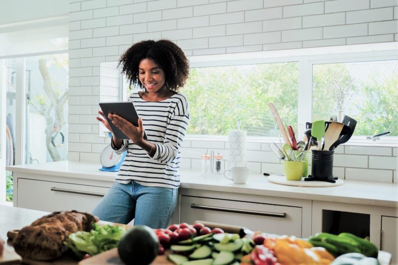 Woman on her tablet in the kitchen looking at Nutrisystem meal plan essentials