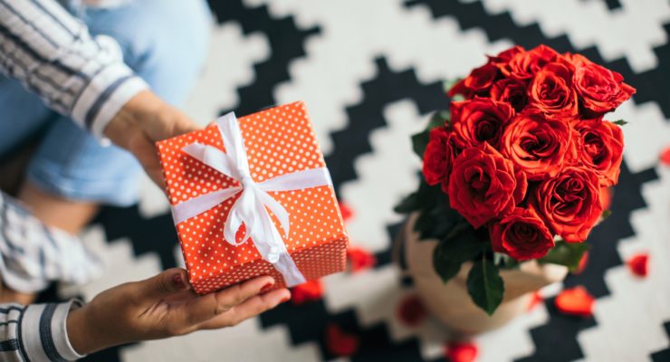 Woman holding Valentine's Day gift next to roses