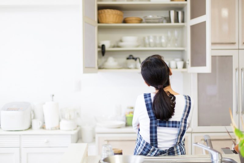 a woman looking at her kitchen cabinet organization
