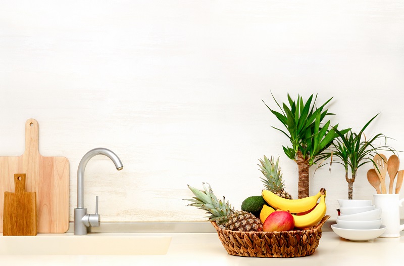 a well-organized kitchen sink with a wicker basket full of fruit