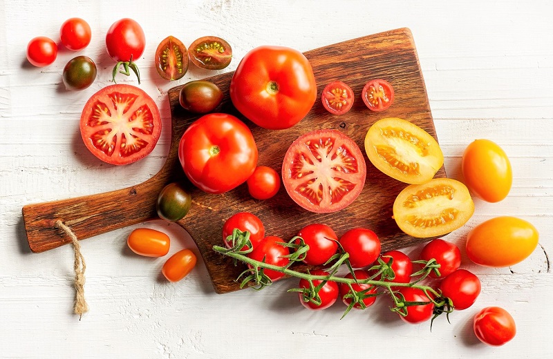 a variety of fresh tomatoes on a wooden cutting board